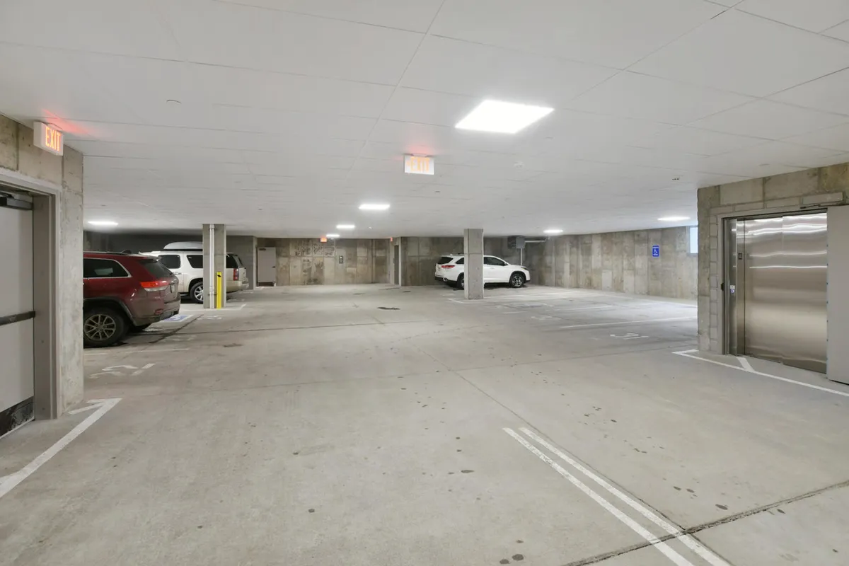This image captures a clean, well-lit underground parking area with elevator access and vehicles parked in designated spots. It conveys a sense of security and convenience for guests arriving by car.