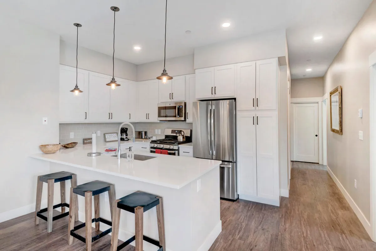 A modern kitchen featuring a central island with seating, stainless steel appliances, and elegant pendant lighting. The space is ready for cooking, casual dining, and heartfelt conversation, making it ideal for hosting and culinary adventures.