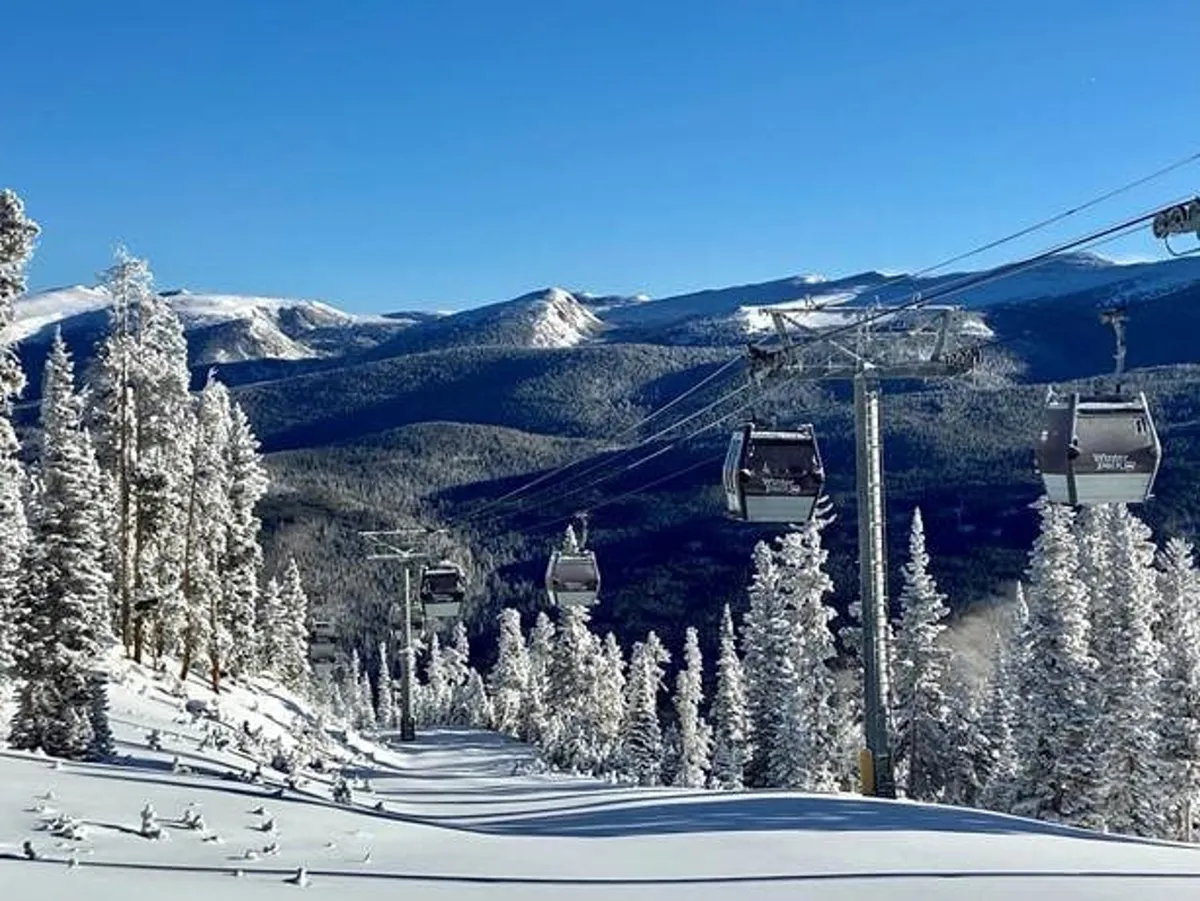 This exterior image features ski lift gondolas gliding above snow-covered trees, with a majestic mountain range in the background. The scene captures the essence of winter sports, highlighting fresh powder on the slopes and the excitement of skiing and snowboarding.