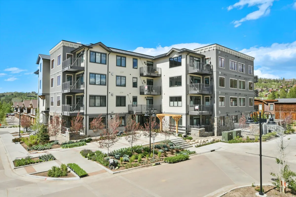 A welcoming exterior shot of a modern building with landscaped gardens and balconies with seating. The environment suggests opportunities for outdoor relaxation and social interaction, reinforcing the connection between indoor comfort and outdoor adventure.