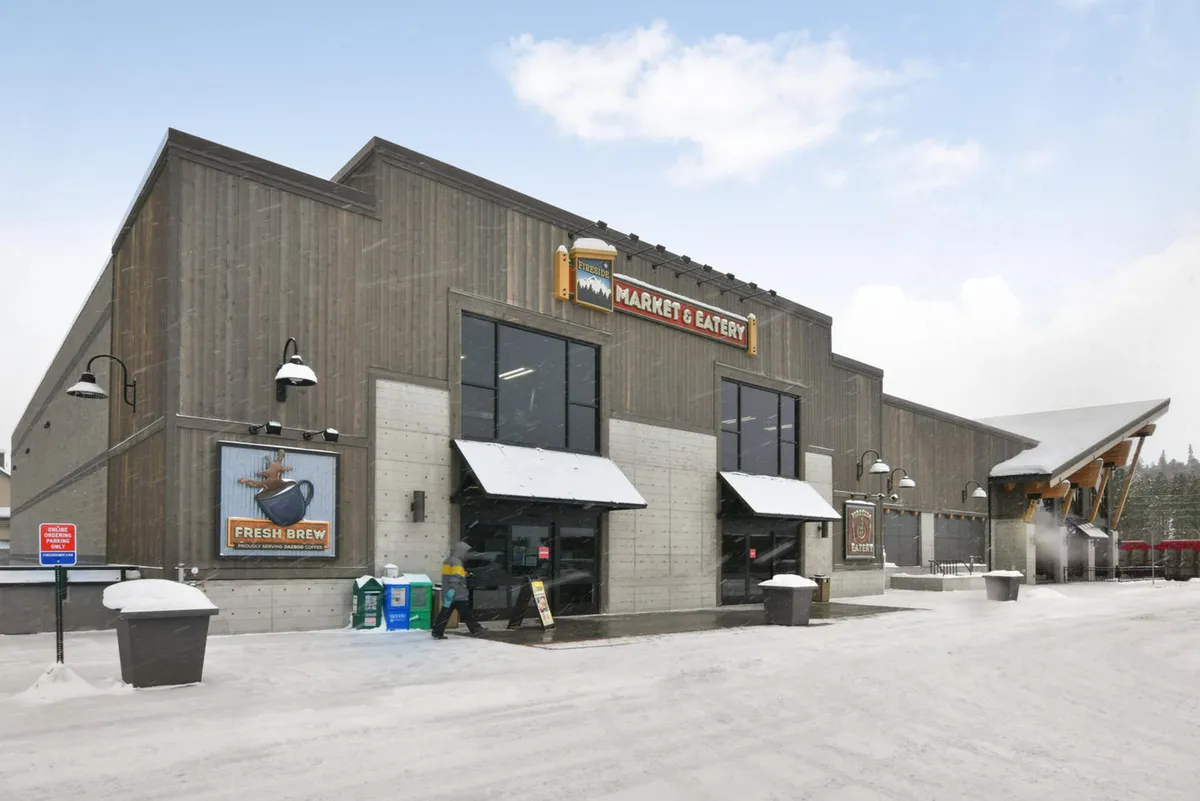 This image displays the exterior entrance of a market in Winter Park, with a prominent sign, inviting doors, and a snowy ground. The setting hints at the active outdoor environment and all-season vibrancy of the area, with local shopping and socializing opportunities.