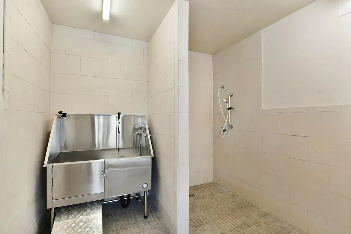 A practical, purpose-built pet wash room with a stainless steel tub and designated shower area, designed for cleaning pets or rinsing off after outdoor activities. The setup is simple and easy to maintain, offering convenience for pet owners and outdoor enthusiasts.